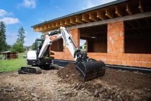 Minibagger E50z bei Erdarbeiten vor einem Rohbau