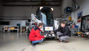 Bobcat-Techniker untersuchen einen Bagger