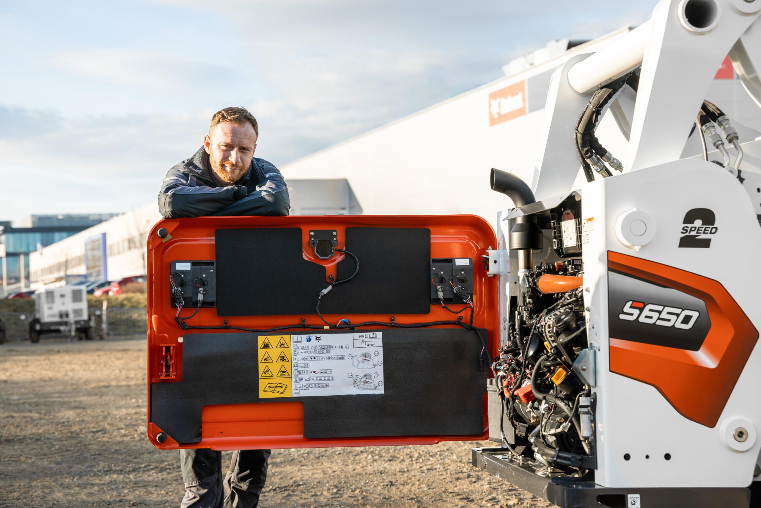 Techniker von Bobcat vor geöffneter Motorhaube eines Kompaktladers