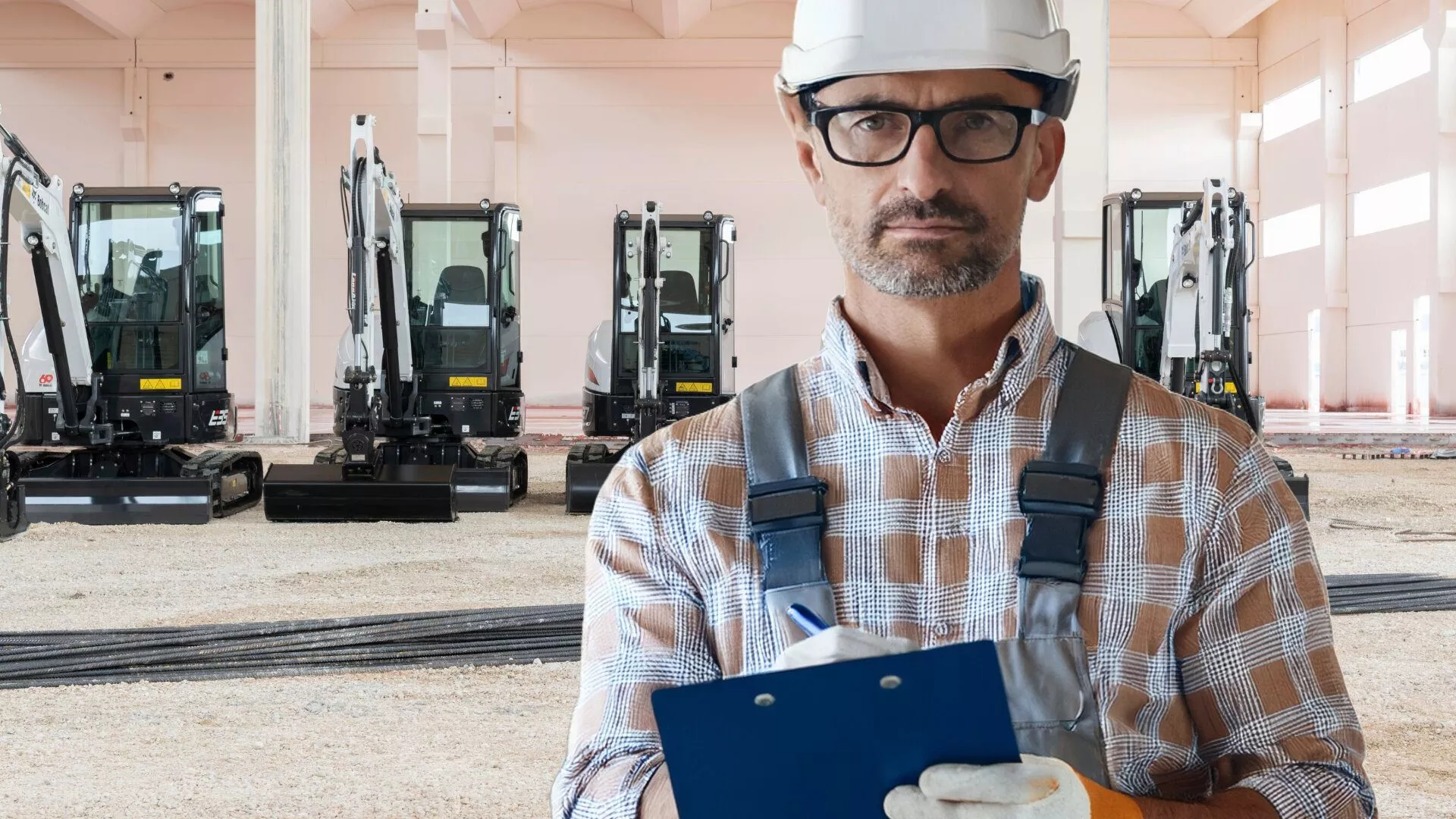 Bauunternehmer in einer Maschinenhalle vor seiner Kompaktbagger-Flotte