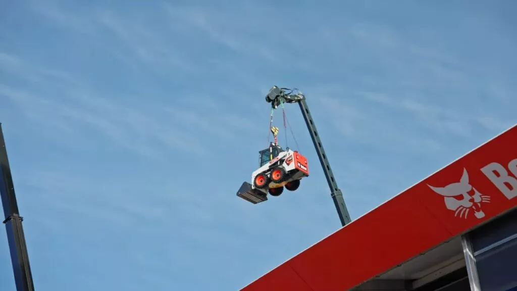 Ein Bobcat-Lader der mit einem Teleskoplader über den Bobcat-Stand auf der BAUMA gehoben wurde
