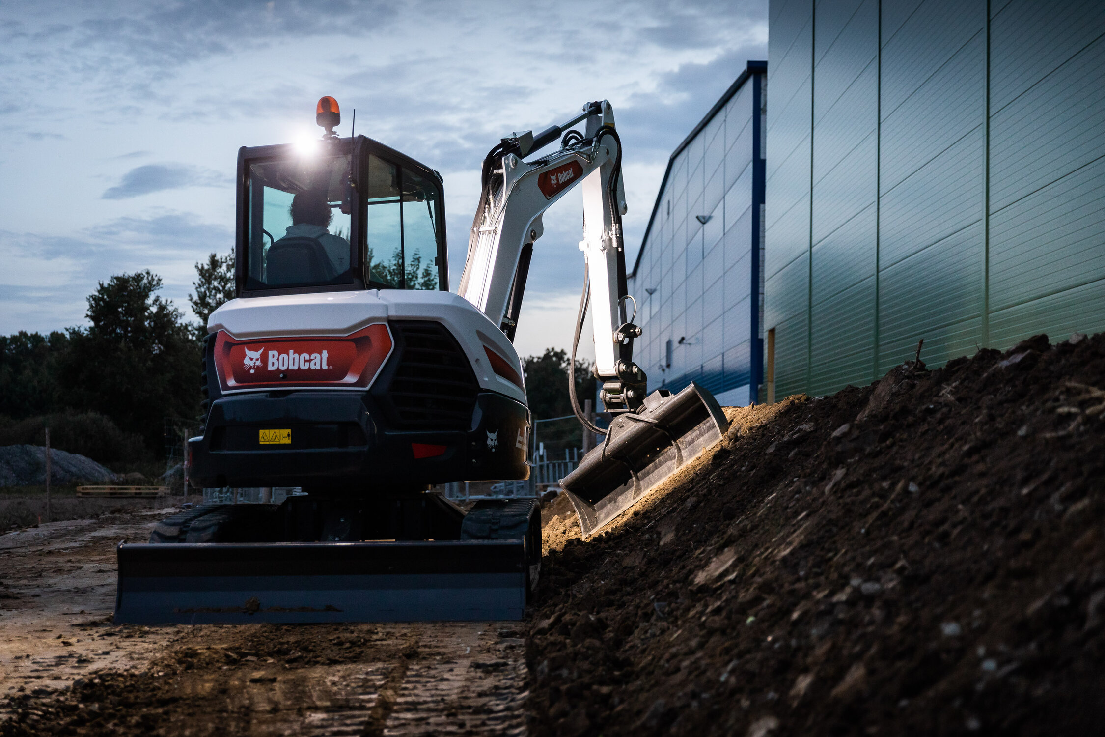 Bobcat Minibagger mit Scheinwerfer bei Abbrucharbeiten in der Dunkelheit